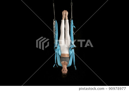 Young woman practice in fly yoga swing hanging upside down on isolated on black background. Aerial gymnastics. Young woman practice in fly yoga swing hanging upside down on isolated on black background. Aerial gymnastics. 90978977
