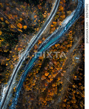 Parallel river and road in autumn forest view from drone 90979492