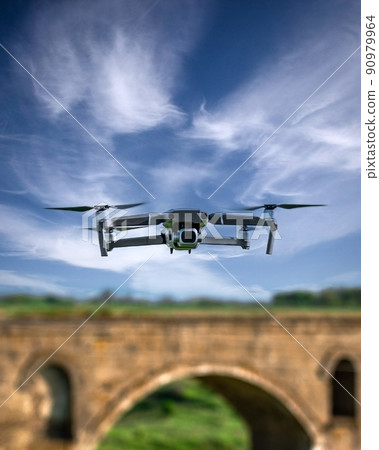 Drone flying over blurred background with old bridge 90979964
