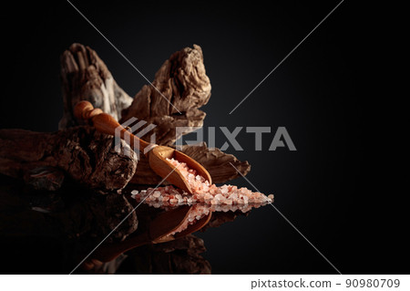 Pink salt with an old snag on a black reflective background. 90980709