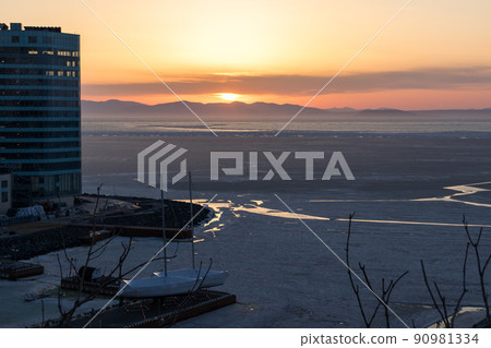 The light of the sun on the horizon on the mountains near the sea with ice. Icy sea and sunset. 90981334