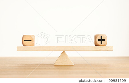 Plus and minus balance concept. Positive and negative symbols on wooden blocks are in balance on a wooden seesaw. Copy space 90981509