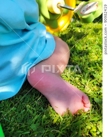cute little baby feet on summer green grass. Pink, delicate skin of the heel, against the background of a bicycle. Summer, day, bright sun. 4k video cute little baby feet on summer green grass. Pink, delicate skin of the heel, against the background of a bicycle. Summer, day, bright sun. 4k video 90982419