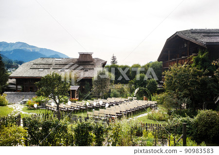 Outdoor wedding ceremony with mountains and buildings in background 90983583