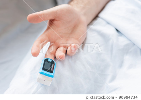 Determination of oxygen in the blood. Male hand with a pulse oximeter on the middle finger, close-up. Top view 90984734