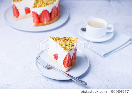 Freesier cake with fresh strawberries and pistachios. French classic dessert. Portion of cake on a white plate close-up. Freesier cake with fresh strawberries and pistachios. French classic dessert. Portion of cake on a white plate close-up. 90984977