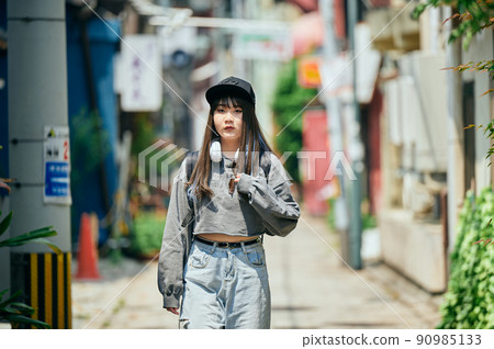 Gen Z woman walking with headphones around her neck 90985133