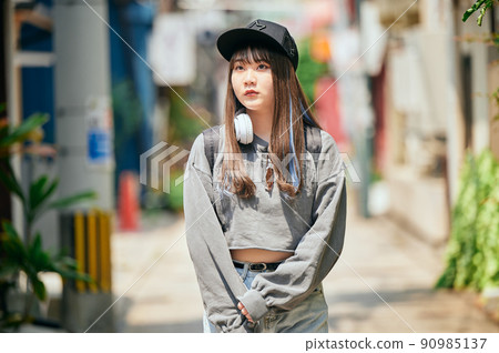Gen Z woman walking with headphones around her neck 90985137