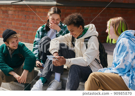 Friends watching funny video on smartphone Friends watching funny video on smartphone 90985870