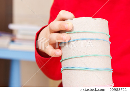 Little boy putting rubber bands or erasers on cardboard roll 90988721