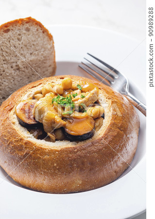 stew with pork meat, chickpeas and sausge in loaf of bread 90989288
