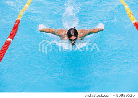 Young muscular man, professional swimmer in goggles training at public swimming-pool, outdoors. Sport, power, energy, style, hobby concept. 90989520