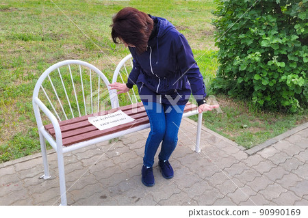 A woman looks with horror at her paint-stained hands after getting up from a painted bench. The inscription on the paper is carefully colored A woman looks with horror at her paint-stained hands after getting up from a painted bench. The inscription on the paper is carefully colored 90990169