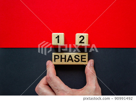 Businessman holds a block with word 'phase'. Wooden cubes with numbers  1 and 2. Beautiful red and black background. Copy space. Concept of choice. 90991492