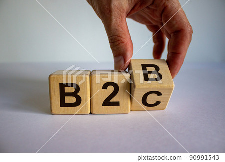Business to Business or Busness to Consumer. Hand turns a cube and changes the expression 'B2B' to 'B2C' or vice versa. Business concept. Beautiful white background, copy space. Business to Business or Busness to Consumer. Hand turns a cube and changes the expression 'B2B' to 'B2C' or vice versa. Business concept. Beautiful white background, copy space. 90991543
