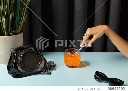 Beautiful groomed womans hands with fashion accessories on blue table. Beautiful groomed womans hands with fashion accessories on blue table. 90992203