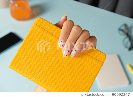 Manicured womans hand holding note pad over blue table. Back to school work from home concept 90992247