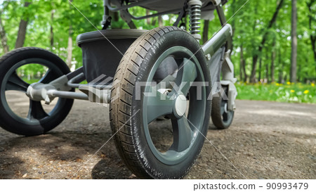 Baby stroller rides back and forth in park on pavement Baby stroller rides back and forth in park on pavement 90993479
