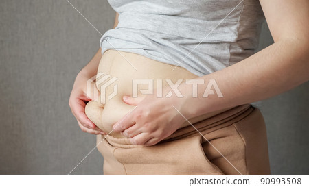 Woman touches fat on flabby sagging belly after pregnancy Woman touches fat on flabby sagging belly after pregnancy 90993508