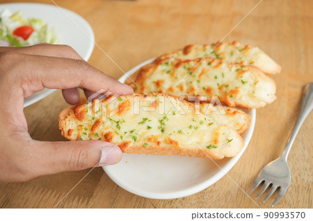 hand pick a garlic bread on a plate hand pick a garlic bread on a plate 90993570
