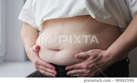Mature woman strokes and squeezes fat belly near windowsill Mature woman strokes and squeezes fat belly near windowsill 90993599