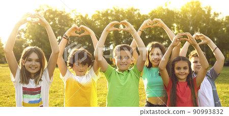 Group of joyful preteen kids standing in sunny park with arms raised show heart shape made by hands Group of joyful preteen kids standing in sunny park with arms raised show heart shape made by hands 90993832