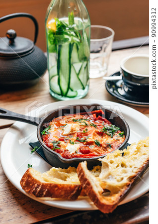 Shakshuka in iron pan served with bread Shakshuka in iron pan served with bread 90994312