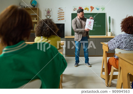 Mature male teacher of anatomy showing students poster of frog structure 90994563