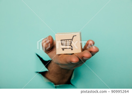 Hand with a delivery box through a blue paper hole Hand with a delivery box through a blue paper hole 90995264