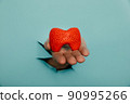 Male hand showing a thyroid out of a hole torn in blue paper wall. Health care, pharmaceutics and medicine advertisement 90995266