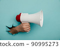 Man's hand arm hold megaphone isolated through torn blue background 90995273