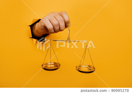 Hand holding metallic scales from yellow torn paper 90995278