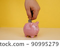 Hand is putting coin into piggy bank. Saving money or investment concept 90995279