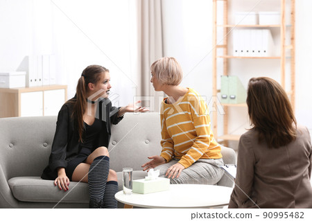 Psychotherapist working with teenage goth girl and her mother in office 90995482