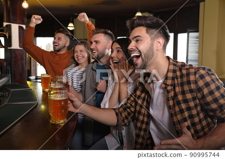 Group of friends watching football in sport bar Group of friends watching football in sport bar 90995744