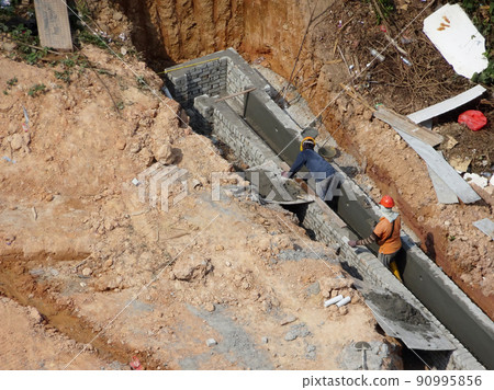 SELANGOR, MALAYSIA -JULY 6, 2021: Construction workers are carrying out daily routines and housekeeping work at a construction site. They are required to wear safety equipment on site. 90995856