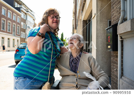 Cheerful moment between an 83 year old senior woman kissing her 39 year old daughter with the Down Syndrome 90995938