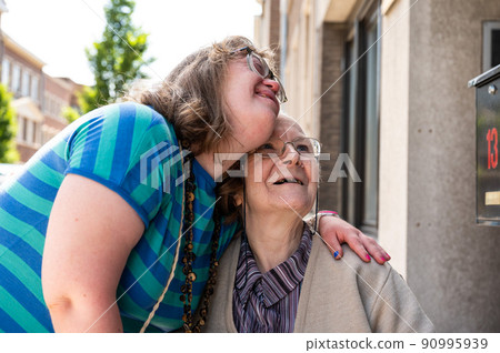 Cheerful moment between an 83 year old senior woman kissing her 39 year old daughter with the Down Syndrome Cheerful moment between an 83 year old senior woman kissing her 39 year old daughter with the Down Syndrome 90995939