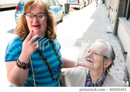 Cheerful moment between an 83 year old senior woman kissing her 39 year old daughter with the Down Syndrome Cheerful moment between an 83 year old senior woman kissing her 39 year old daughter with the Down Syndrome 90995941