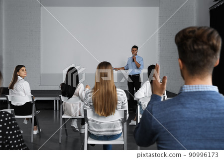 Male business trainer giving lecture in conference room with projection screen Male business trainer giving lecture in conference room with projection screen 90996173