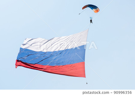 Skydiver in the sky with a giant flag of Russia against the blue sky. 90996356