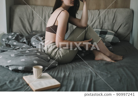 Young sexy woman portrait in bed with a book and coffee cup in the morning. Young sexy woman portrait in bed with a book and coffee cup in the morning. 90997241