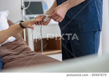 Nurse checking with fingertip pulse oximeter oxygen saturation of patient blood in hospital Nurse checking with fingertip pulse oximeter oxygen saturation of patient blood in hospital 90997679