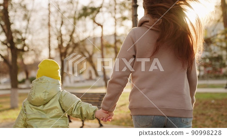 little child kid holding mother hand. closeup hands glare sun. child hand holding mom. child walk with parent park. chidhood dream. weekend park with mom. happy family vacation. walk city park sunset. little child kid holding mother hand. closeup hands glare sun. child hand holding mom. child walk with parent park. chidhood dream. weekend park with mom. happy family vacation. walk city park sunset. 90998228