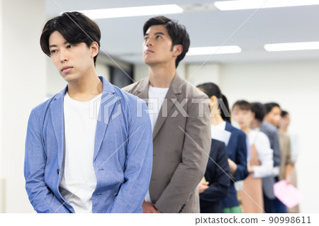 Men and women in a line waiting for their turn 90998611