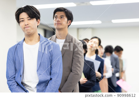 Men and women in a line waiting for their turn 90998612