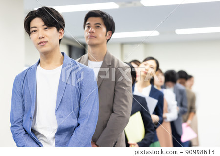 Men and women in a line waiting for their turn 90998613