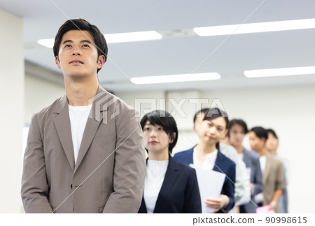 Men and women in a line waiting for their turn 90998615