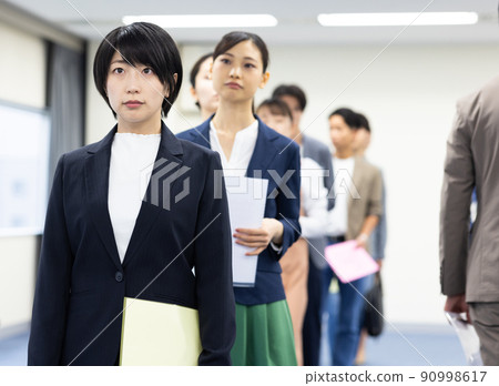 Men and women in a line waiting for their turn 90998617