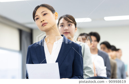 Men and women in a line waiting for their turn 90998619